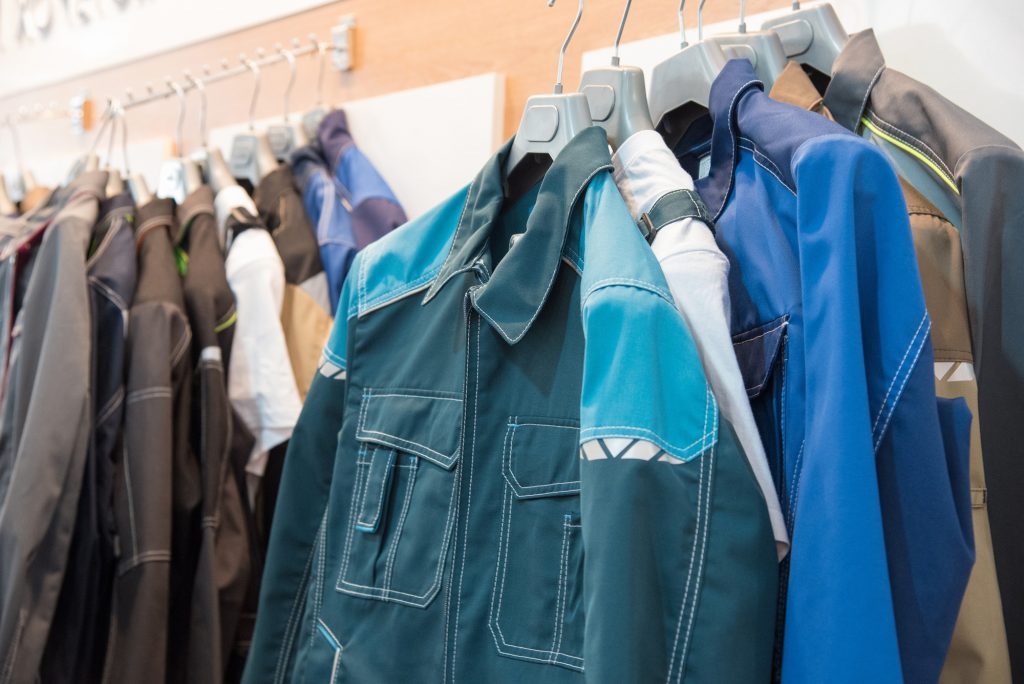 Rack of work jackets in blue, teal, and gray tones hanging in a store, orderly mood