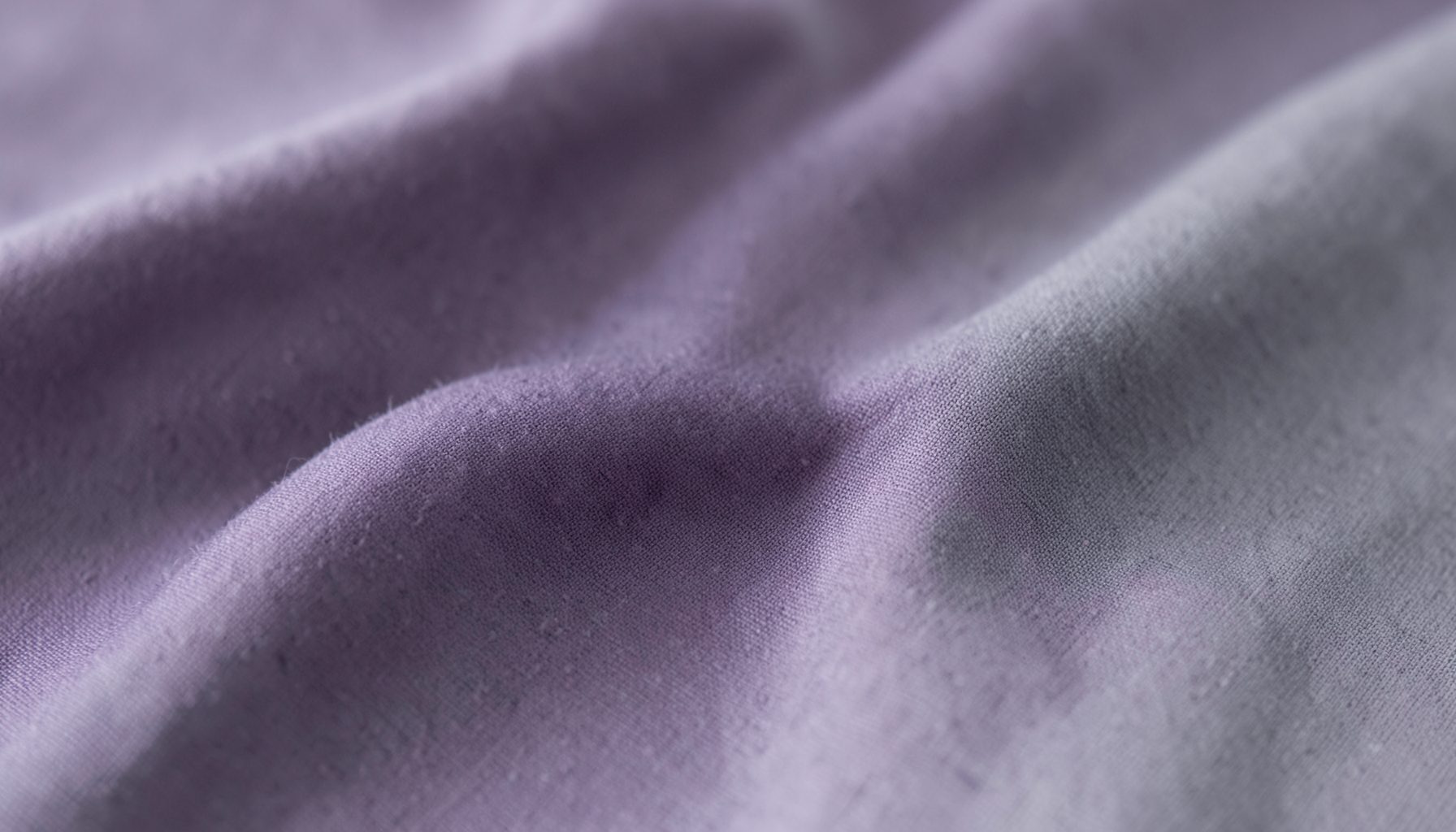 Softly lit fabric texture in muted purple and gray tones, calm and professional mood